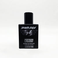 Front-facing studio product shot of Bravo Zulu VIXEN Extrait de Parfum by Flagship Soap Company. The heavy matte black glass bottle with matching black cap is centered on a clean white background, displaying the silver BRAVO ZULU B★Z winged logo, VIXEN name, Extrait de Parfume 1.7 FL OZ / 50 ML, and Made in USA text.