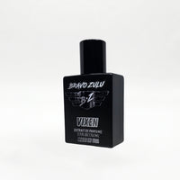 Close angled product shot of the Bravo Zulu VIXEN Extrait de Parfum bottle by Flagship Soap Company, showing the matte black glass bottle and black cap with silver BRAVO ZULU B★Z winged logo and VIXEN branding, set against a seamless white studio background.