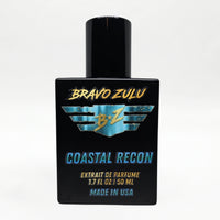 Front-facing studio product shot of Bravo Zulu COASTAL RECON Extrait de Parfum by Flagship Soap Company. The heavy matte black glass bottle with matching black cap is centered on a clean white background, displaying the turquoise-and-gold BRAVO ZULU B★Z winged logo, COASTAL RECON name, Extrait de Parfume 1.7 FL OZ / 50 ML, and Made in USA text.