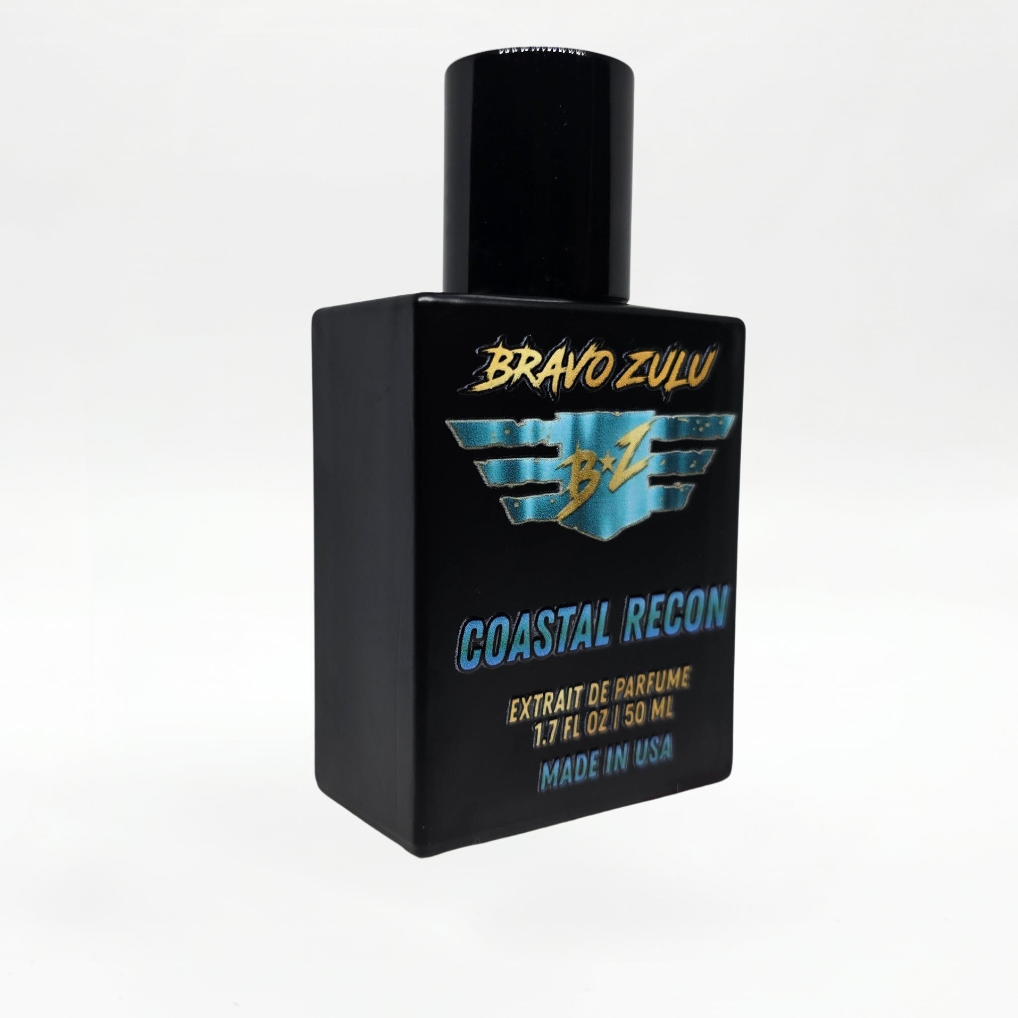 Angled three-quarter studio shot of the Bravo Zulu COASTAL RECON Extrait de Parfum bottle by Flagship Soap Company, showing the matte black glass bottle and black cap with turquoise-and-gold BRAVO ZULU B★Z winged logo and COASTAL RECON branding, set against a seamless white studio background.