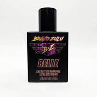 Front-facing studio product shot of Bravo Zulu BELLE Extrait de Parfum by Flagship Soap Company. The heavy matte black glass bottle with matching black cap is centered on a clean white background, displaying the maroon-and-gold BRAVO ZULU B★Z winged logo, BELLE name, Extrait de Parfume 1.7 FL OZ / 50 ML, and Made in USA text.