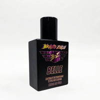 Angled studio shot of the Bravo Zulu BELLE Extrait de Parfum bottle by Flagship Soap Company, showing the matte black glass bottle and black cap with maroon-and-gold BRAVO ZULU B★Z winged logo and BELLE branding, set against a seamless white studio background.