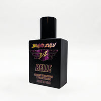 Three-quarter angled studio shot of the Bravo Zulu BELLE Extrait de Parfum bottle by Flagship Soap Company, rotated to show the maroon-and-gold BRAVO ZULU B★Z winged logo and BELLE name from a different perspective, on a seamless white studio background.