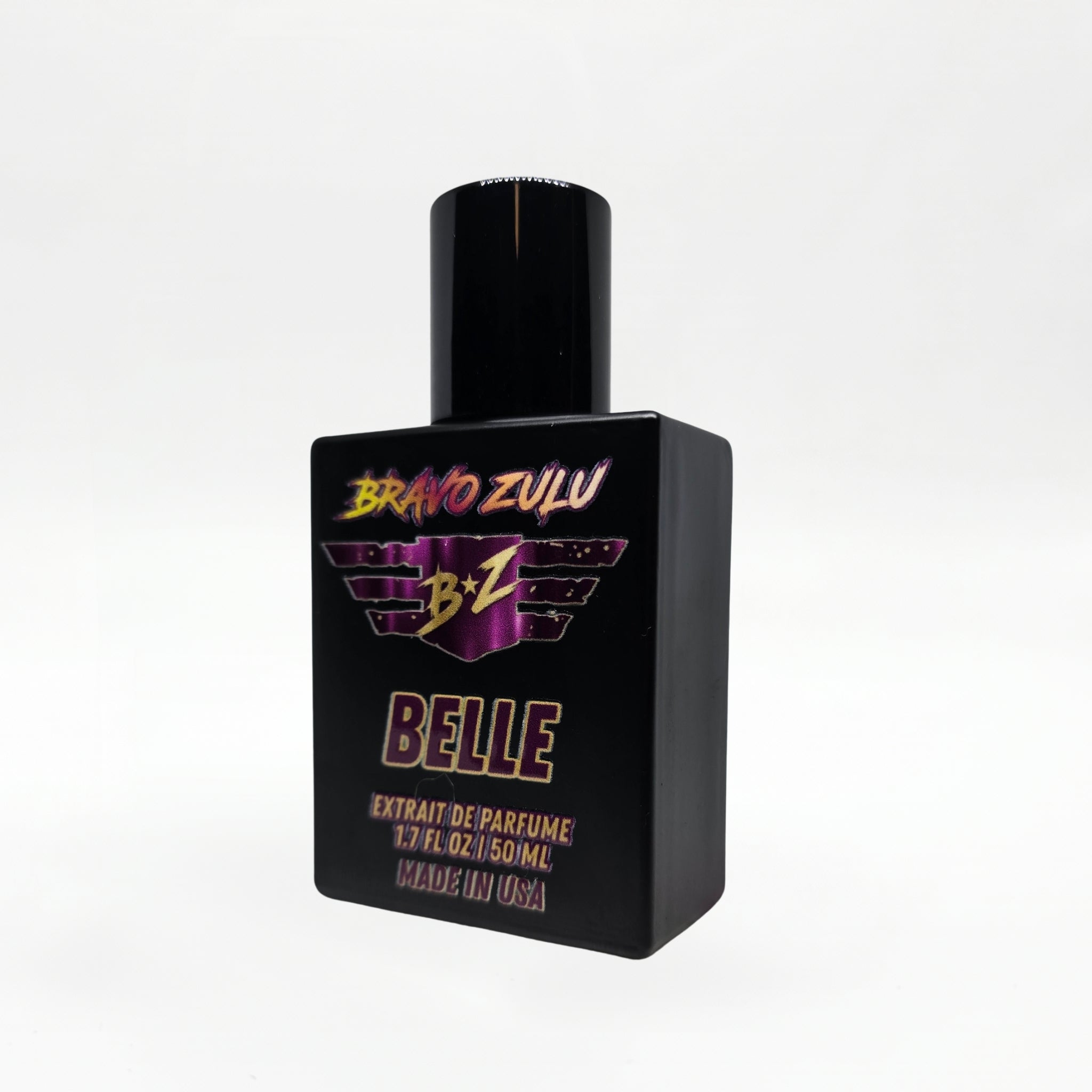 Three-quarter angled studio shot of the Bravo Zulu BELLE Extrait de Parfum bottle by Flagship Soap Company, rotated to show the maroon-and-gold BRAVO ZULU B★Z winged logo and BELLE name from a different perspective, on a seamless white studio background.