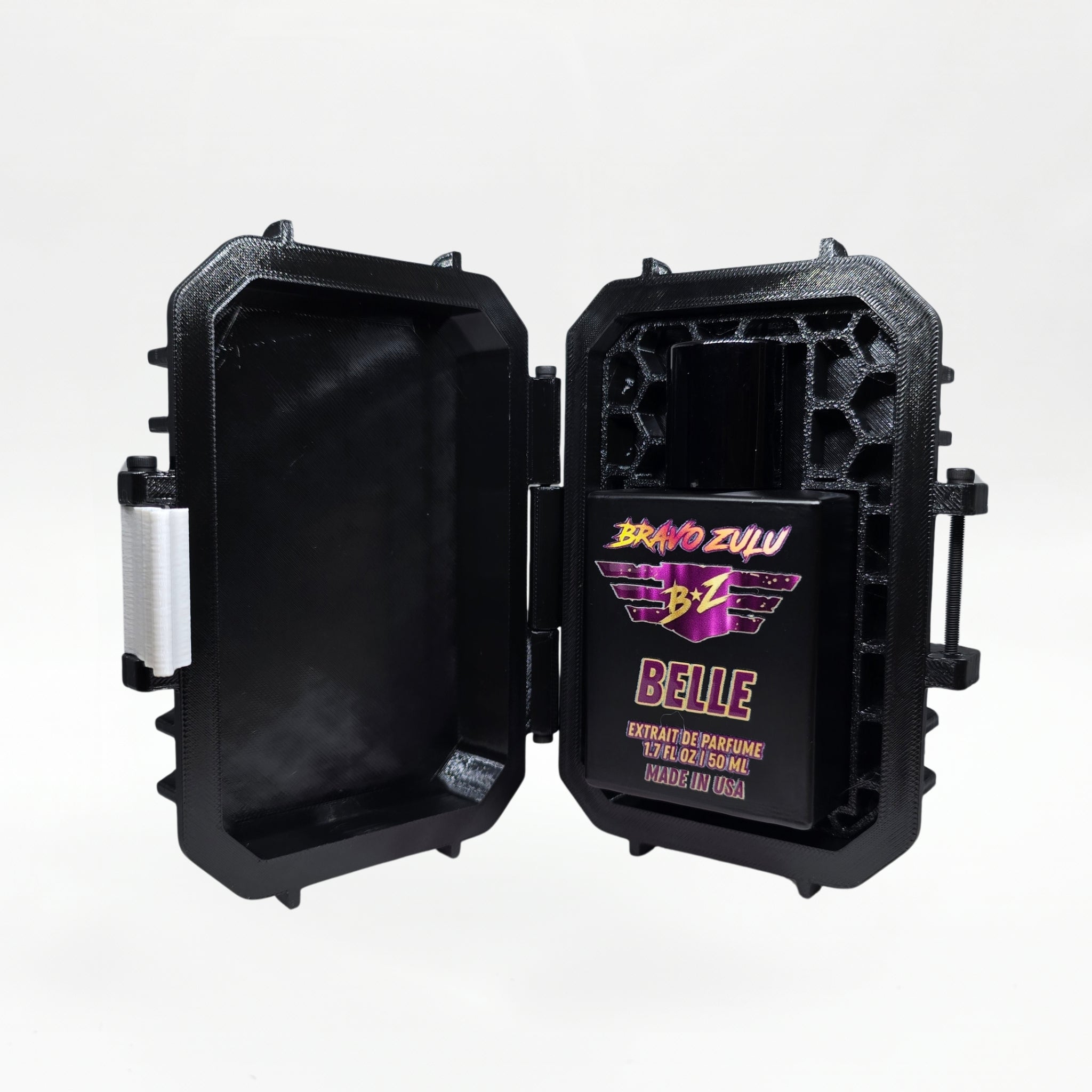 Bravo Zulu BELLE Extrait de Parfum by Flagship Soap Company shown docked inside its open black rugged tactical case, the matte black glass bottle secured in the honeycomb interior insert opposite the white foam-lined lid, on a seamless white studio background.