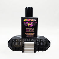 Bravo Zulu BELLE Extrait de Parfum bottle by Flagship Soap Company balanced on top of its closed black rugged tactical case, the matte black glass bottle displaying the maroon-and-gold BRAVO ZULU B★Z winged logo and BELLE name, on a seamless white studio background.