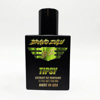 Front-facing studio product shot of Bravo Zulu TIPSY Extrait de Parfum by Flagship Soap Company. The heavy matte black glass bottle with matching black cap is centered on a clean white background, displaying the lime-green BRAVO ZULU B★Z winged logo, TIPSY name, Extrait de Parfume 1.7 FL OZ / 50 ML, and Made in USA text.