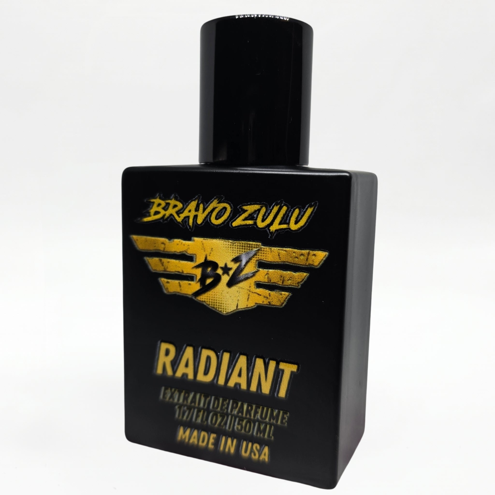 Bravo Zulu RADIANT Extrait de Parfum bottle by Flagship Soap Company balanced on top of its closed yellow-and-black rugged tactical case, the matte black glass bottle displaying the gold BRAVO ZULU B★Z winged logo and RADIANT name, on a seamless white studio background.