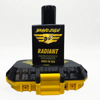 Bravo Zulu RADIANT Extrait de Parfum by Flagship Soap Company shown docked inside its open yellow rugged tactical case, the matte black glass bottle secured in the black honeycomb interior insert opposite the empty lid, on a seamless white studio background.