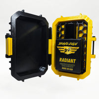 Closed black-and-yellow rugged tactical travel case for Bravo Zulu RADIANT Extrait de Parfum by Flagship Soap Company, front view showing the gold BRAVO ZULU B★Z winged logo on the case exterior, on a seamless white studio background.
