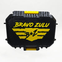 Bravo Zulu RADIANT Extrait de Parfum by Flagship Soap Company displayed side by side with its closed yellow-and-black rugged tactical case featuring the gold BRAVO ZULU B★Z winged logo, on a clean white studio background.
