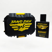 Alternate three-quarter angled studio shot of the Bravo Zulu RADIANT Extrait de Parfum bottle by Flagship Soap Company, rotated to show the gold-and-black BRAVO ZULU B★Z winged logo and RADIANT name from a different perspective, on a seamless white studio background.