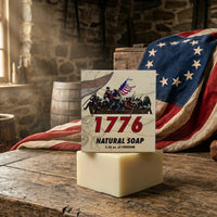 1776 Bay Rum Natural Men's Soap by Patriot and Company, 5.56 oz. of Freedom, Displayed on a Rustic Distressed Oak Workbench in an 18th Century Colonial Workshop with a Betsy Ross Flag and Quill Pen.