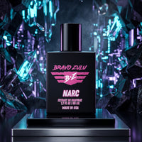 Front hero shot of Bravo Zulu NARC Extrait de Parfum men's cologne bottle prominently displayed on a sleek metallic pedestal. The tactical matte black glass bottle features a striking pink and white logo design. The background creates a super cool contrast with sharp, futuristic crystal structures illuminated by brilliant cyan, teal, and purple neon light accents.
