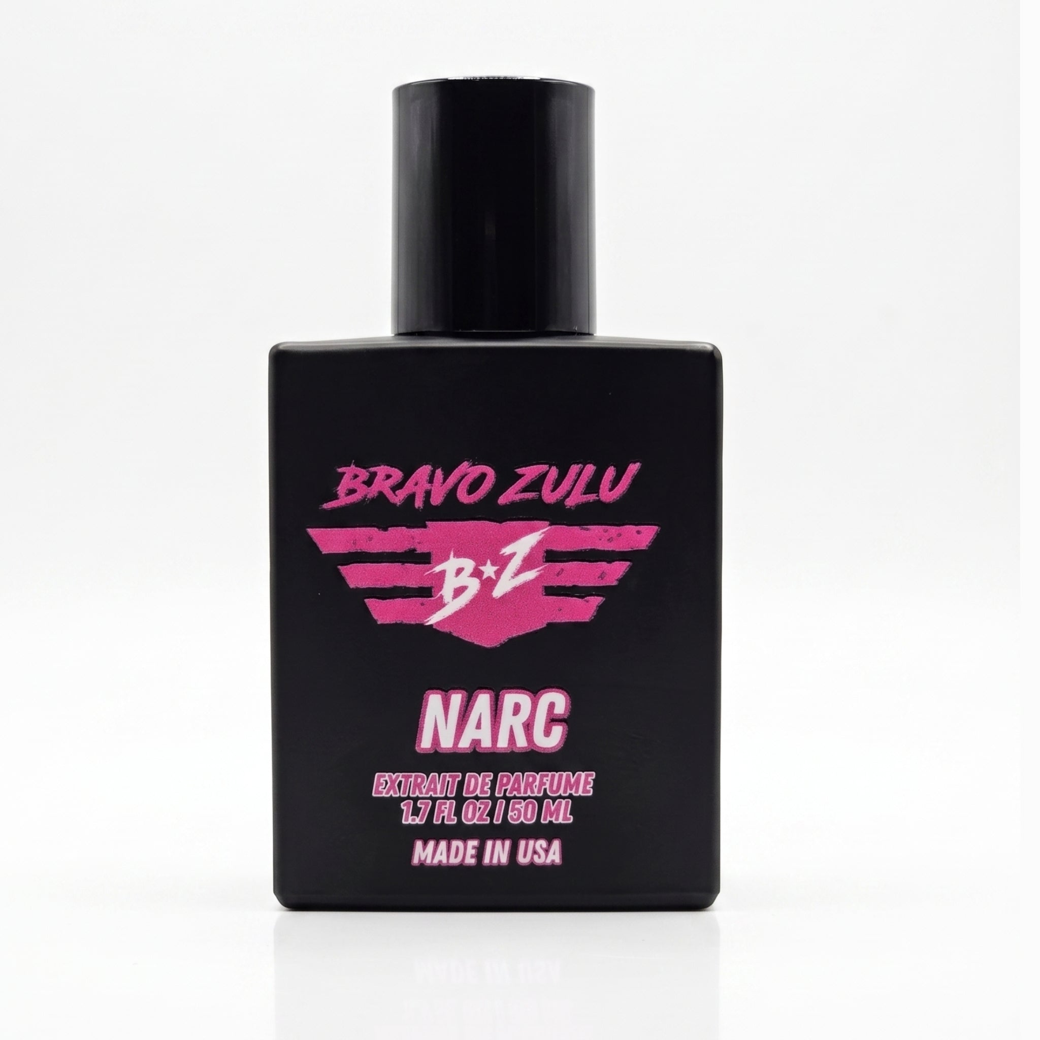 Straight-on product shot of Bravo Zulu NARC Extrait de Parfum men's cologne bottle centered on a solid white background. The heavy tactical matte black glass bottle is shown from the front, perfectly highlighting the vibrant pink and white "B★Z NARC" logo, "Extrait de Parfum," and "Made in USA" label details with a subtle reflection below.