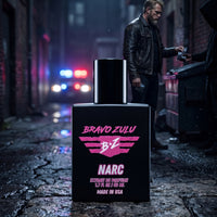 Front shot of Bravo Zulu NARC Extrait de Parfum cologne bottle in tactical matte black glass with pink branding. The premium 30% concentration masculine fragrance sits on wet cobblestone in a dark, gritty alleyway. In the background, a calculated undercover detective operates in the shadows next to a dumpster, with blurred police lights flashing in the night.