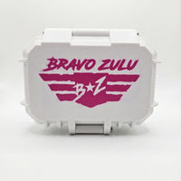 Front studio product shot of the rugged white custom tactical case for Bravo Zulu NARC Extrait de Parfum cologne, isolated on a seamless white background. The closed, heavy-duty protective hardware case displays a bold pink stenciled "Bravo Zulu B★Z" wing logo centered across the front, offering a high-yield, gift-ready presentation for the premium 30% concentration men's fragrance.