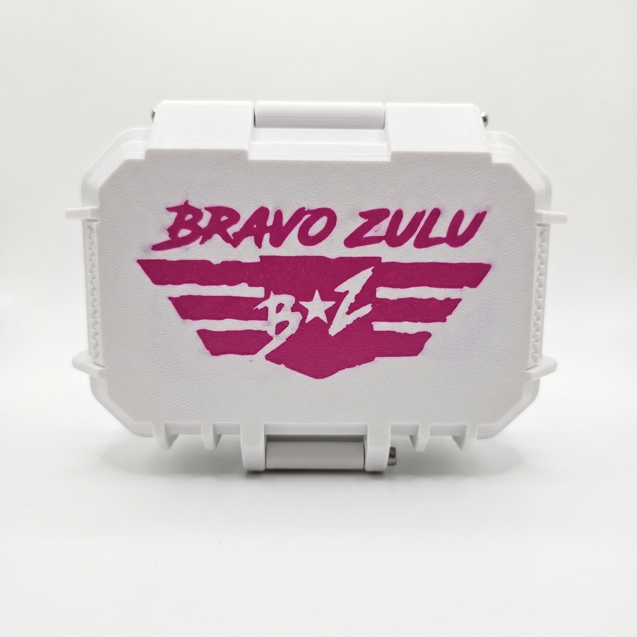 Front studio product shot of the rugged white custom tactical case for Bravo Zulu NARC Extrait de Parfum cologne, isolated on a seamless white background. The closed, heavy-duty protective hardware case displays a bold pink stenciled "Bravo Zulu B★Z" wing logo centered across the front, offering a high-yield, gift-ready presentation for the premium 30% concentration men's fragrance.