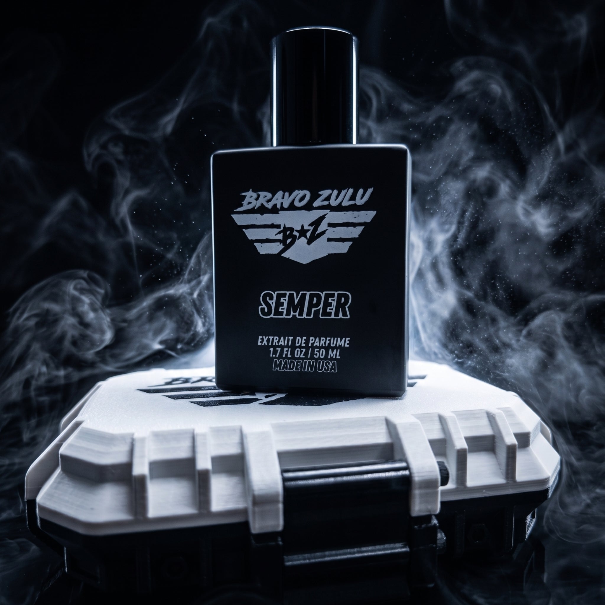 A dynamic, tactical product photograph for SEMPER Extrait de Parfum by Bravo Zulu. A heavy, matte black glass bottle, featuring a distinct white B+Z winged shield logo and bold 'SEMPER' branding, stands centrally on its custom white and black rugged tactical protective case. The complex scene is enveloped in dramatic, cool-toned smoke and mist against a dark, low-key background, visualizing the cold ocean marine and rugged earthy woods scent profile. Key keywords integrated into the visual description inclu