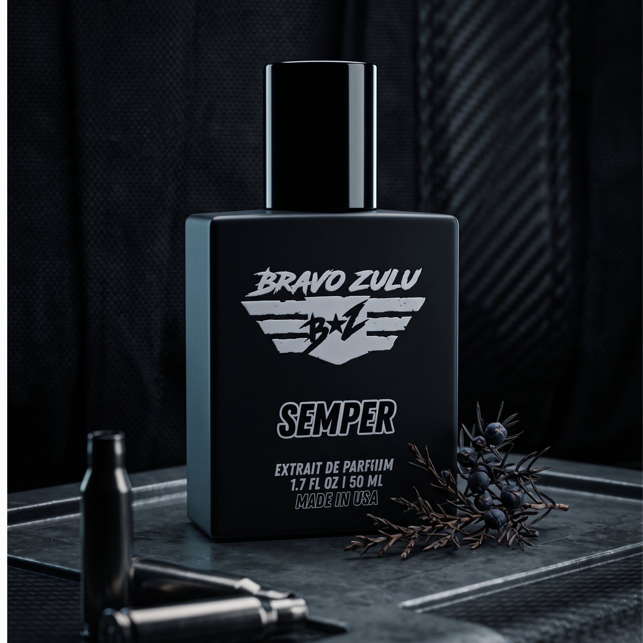A tactical product image of SEMPER Extrait de Parfum by Bravo Zulu. The heavy matte black glass bottle is positioned on a rugged, weathered armor plate alongside dark metal shell casings and a fresh, cold juniper branch with blue berries, showcasing the scent's rugged earthy woods foundation. The background features a dark carbon fiber texture, capturing an elite, heavy-duty aesthetic engineered for a commanding, unyielding presence.