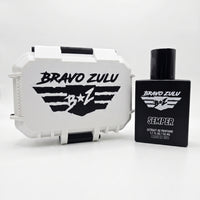 A side-by-side e-commerce product shot of SEMPER Extrait de Parfum by Bravo Zulu on a seamless white background. On the right stands the heavy tactical matte black glass bottle, featuring crisp white flight-wing branding. On the left is the matching custom-engineered, rugged protective case finished in clean Vanguard White with aggressive matte black contrast accents and a bold, black flight-wing logo. This elite, American-built cologne represents a heavy-duty standard of quality engineered for a commanding