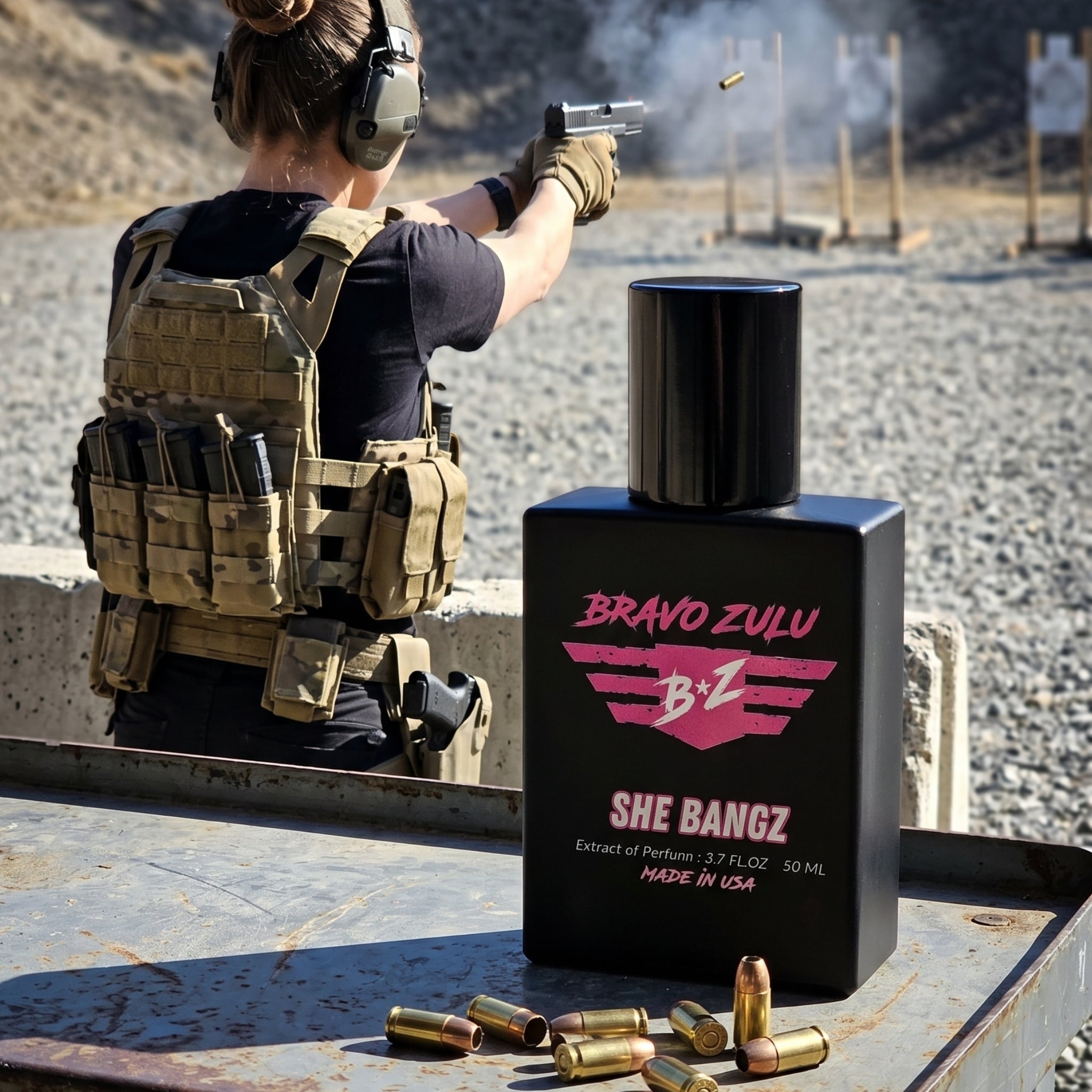 Shopify product lifestyle image for SHE BANGZ Extrait de Parfum from the Bravo Zulu Lineup by Flagship Soap Company. In the foreground, the heavy, tactical matte black glass bottle sits on a weathered metal shooting bench alongside scattered brass handgun cartridges and live ammunition. The bottle features a sleek black cap and striking hot pink branding for "BRAVO ZULU" and "SHE BANGZ," highlighting its American-built quality and high-impact formula (Extrait de Parfum / MADE IN USA). In the background, a w