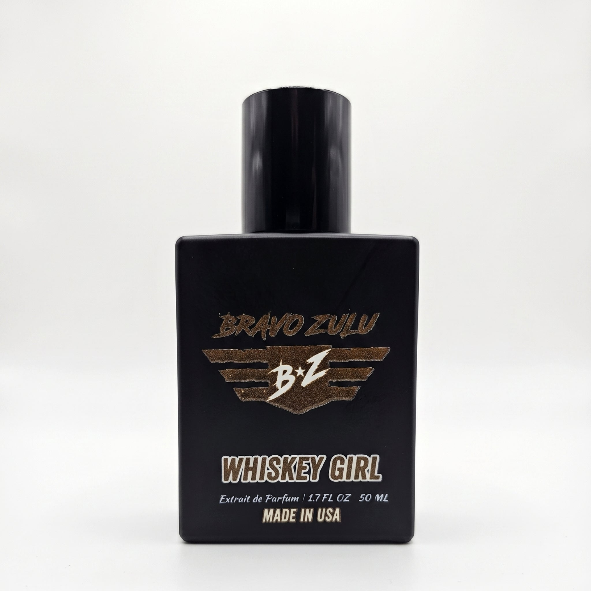 Front-facing view of Whiskey Girl Extrait de Parfum by Flagship Soap Company. The perfume is housed in a heavy, tactical matte black glass bottle featuring the gold-embossed Bravo Zulu wing logo. Below the logo, text reads "WHISKEY GIRL", "Extrait de Parfum | 1.7 FL OZ 50 ML", and "MADE IN USA", set against a clean, white background.