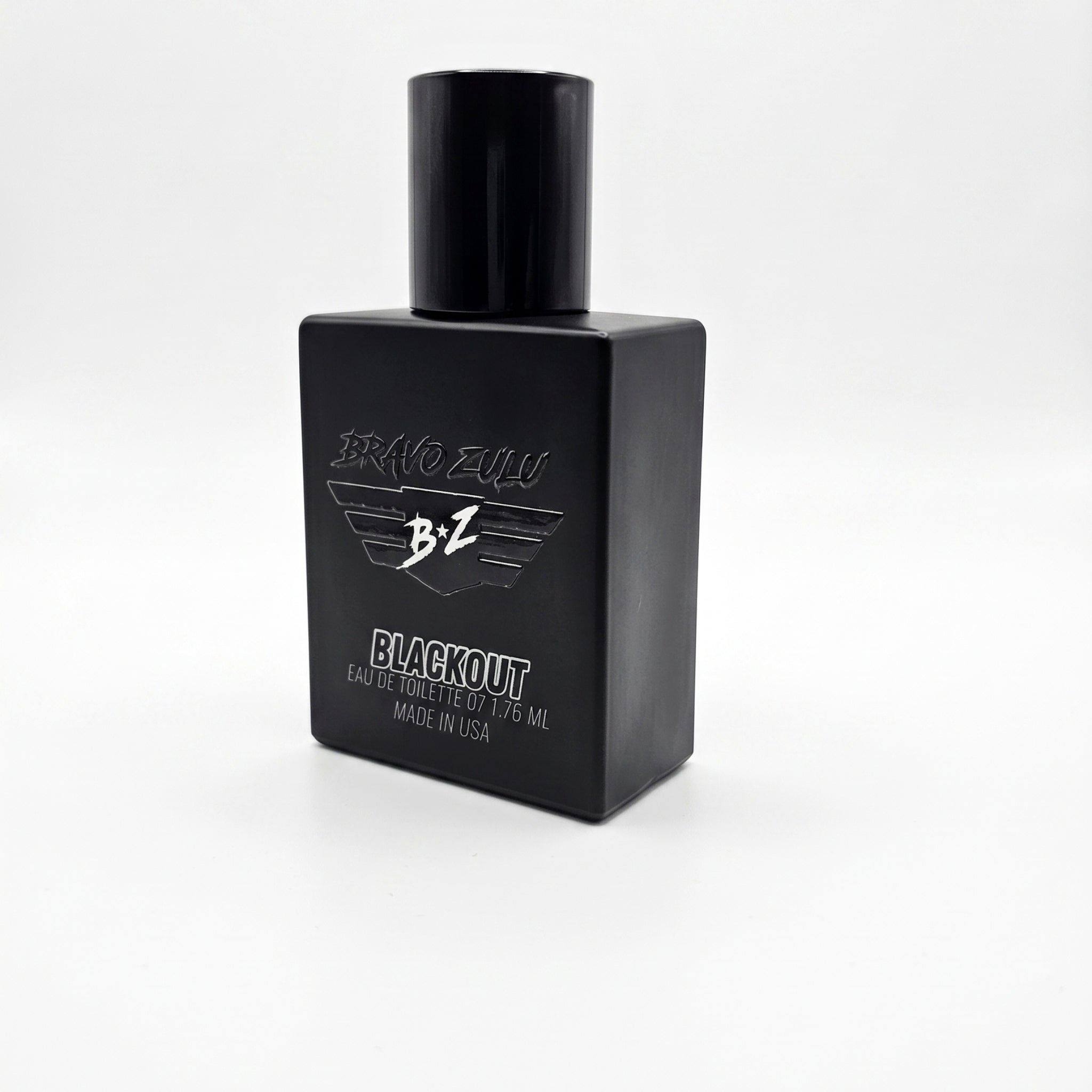 A product shot of a 40ml compact footprint bottle of BLACKOUT Extrait de Parfum from Flagship Soap Company, an aggressive, tactical masterpiece engineered for the men who run toward the chaos. The matte black glass bottle is heavy and tactical, designed to block UV light. The hardware includes a monochromatic Stealth Black cap and an Ultra-Fine Professional-Grade Atomizer that delivers a pressurized, micro-fine mist. On the front, minimalist white text reads 'BRAVO ZULU' above 'BLACKOUT', with smaller text 