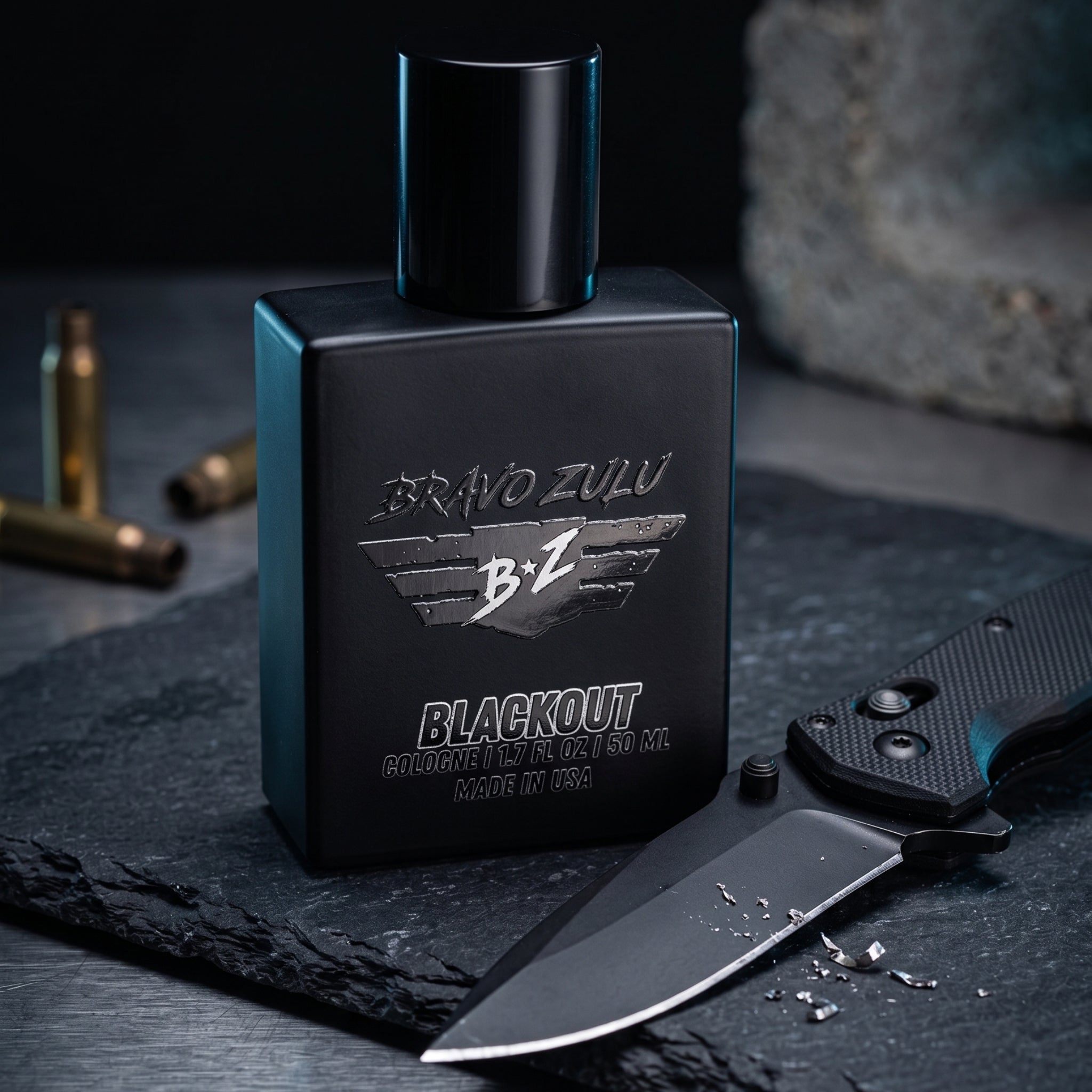 Bravo-Zulu-Flagship-Soap-Company-Extrait-De-Parum-Fragrance-Cologne-Bottle-Knife.jpg depicts the compact 40ml matte black glass bottle of Bravo Zulu Flagship Soap Company's BLACKOUT Extrait de Parfum. The heavy, tactical masterpiece sits on a textured slate surface, its monochromatic Stealth Black design featuring silver embossed 'BRAVO ZULU' and 'BLACKOUT' logos, and 'MADE IN USA' text, all engineered for the men who defend the perimeter. Next to it, a black tactical folding knife with a textured grip and 