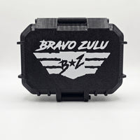 A crisp, studio e-commerce product shot centered on a solid white background, highlighting the rugged stealth black hardware for the BLACKOUT product line by Flagship Soap Company. The image captures the front face of the custom-engineered, tactical protective case, which is tightly sealed to show its ultra-durable, mission-ready build. The textured matte black surface features a bold, high-contrast white embossed design showcasing the stylized 'BRAVO ZULU' typography stacked cleanly above the signature win