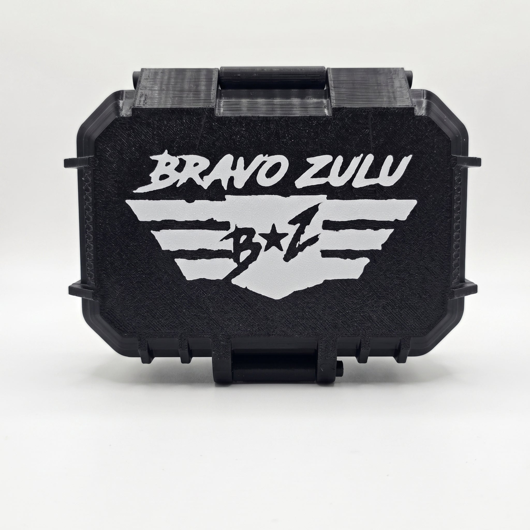 A crisp, studio e-commerce product shot centered on a solid white background, highlighting the rugged stealth black hardware for the BLACKOUT product line by Flagship Soap Company. The image captures the front face of the custom-engineered, tactical protective case, which is tightly sealed to show its ultra-durable, mission-ready build. The textured matte black surface features a bold, high-contrast white embossed design showcasing the stylized 'BRAVO ZULU' typography stacked cleanly above the signature win