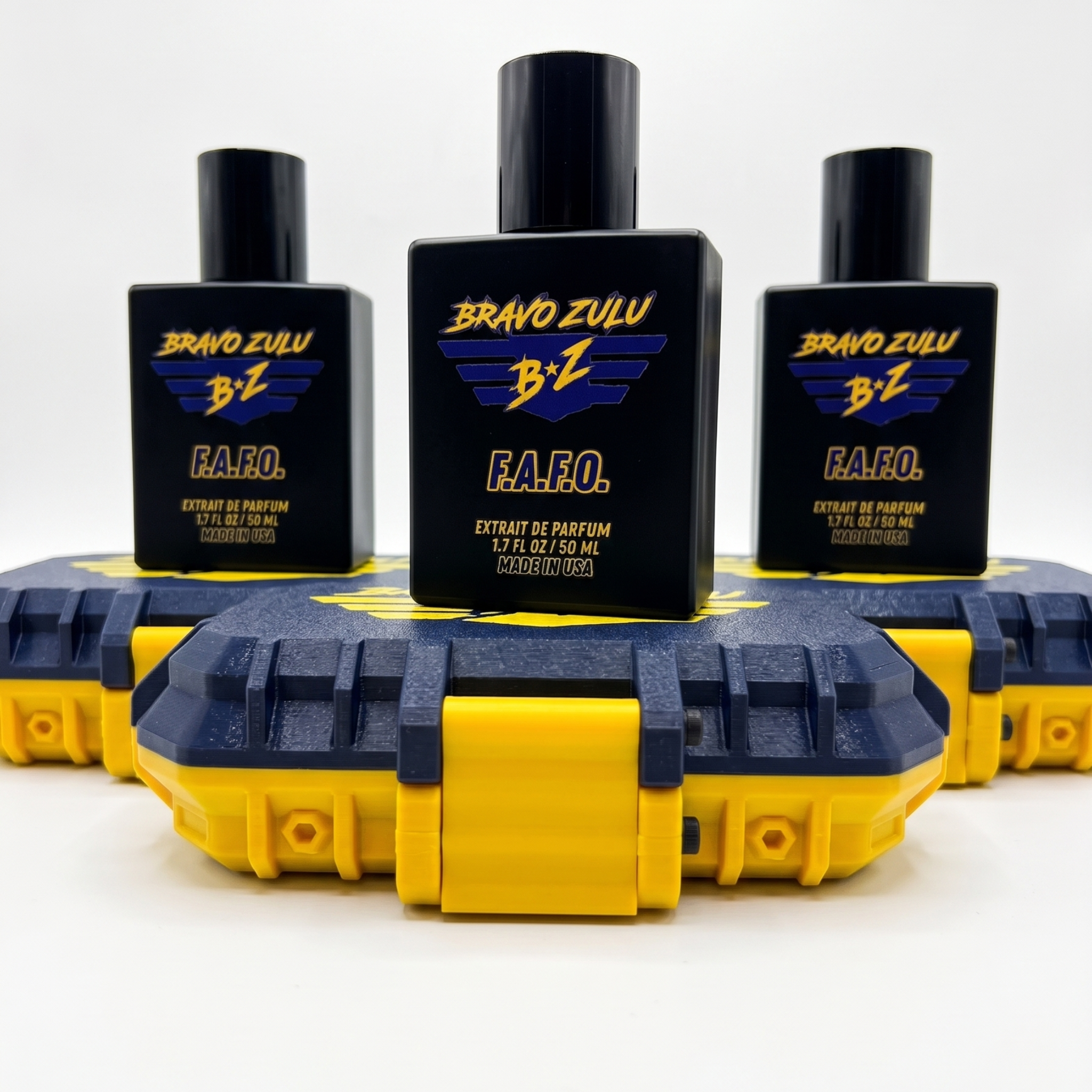 A three-bottle collection image of F.A.F.O. Extrait de Parfum by Flagship Soap Company. Three tactical matte black glass cologne bottles are arranged in a pyramid formation, each sitting on top of its own custom-engineered rugged protective case. The cases showcase a textured Tactical Blue finish with high-visibility Strike Yellow contrast accents and latches. Each bottle prominently displays the purple and yellow Bravo Zulu BZ logo, representing an elite 30% concentration fragrance built for uncompromising