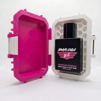 Front-facing product shot of the Bravo Zulu MERICAN WOMAN Extrait de Parfum perfume bottle nestled inside its custom-engineered tactical case, propped fully open on a clean white background. The tactical matte black glass bottle is securely locked into the right side of the white, honeycomb-textured interior base, cleanly displaying the bold pink and white winged B★Z logo and product text. The matching rugged lid stands open on the left, finished in a vibrant Elite Pink with a clean white contrast latch. Fo