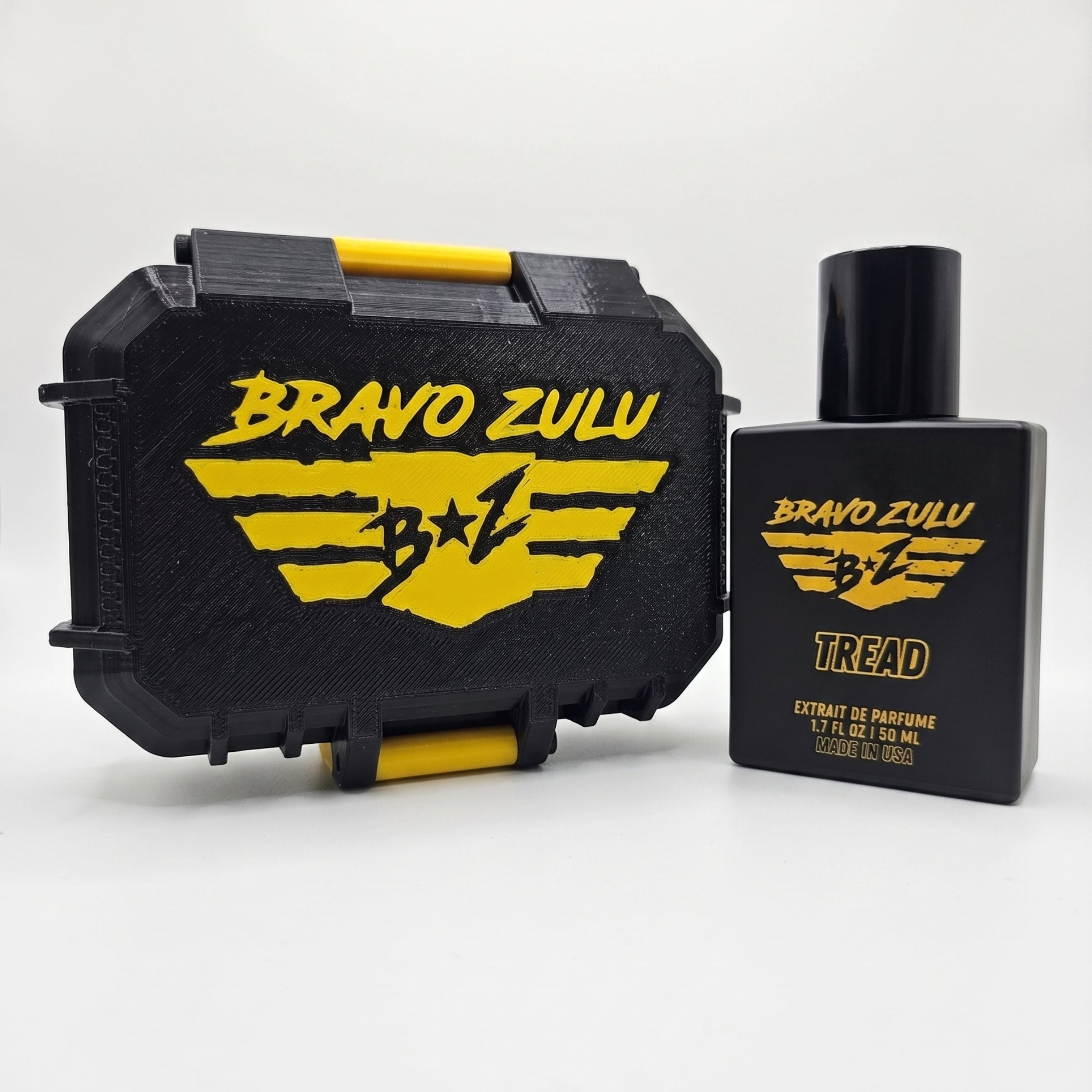Flagship Soap Company TREAD Extrait de Parfum cologne bottle shown alongside its custom tactical case on a seamless white background. Both the matte black glass fragrance bottle and the rugged, heavy-duty protective case feature the striking yellow Bravo Zulu brand logo, emphasizing an aggressive, tactical presentation.