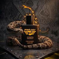 Dramatic, high-impact product image for TREAD Extrait de Parfum by Flagship Soap Company. In the center, a tactical matte black glass bottle is wrapped by a realistic, coiled rattlesnake with its rattle raised in the foreground and its head focused forward. The bottle features the striking yellow "Bravo Zulu" winged logo, the name "TREAD", and base text reading "EXTRAIT DE PARFUME | 1.7 FL OZ | 50 ML | MADE IN USA". The scene is set on a dark, riveted metal surface with cinematic smoke. In the background, a