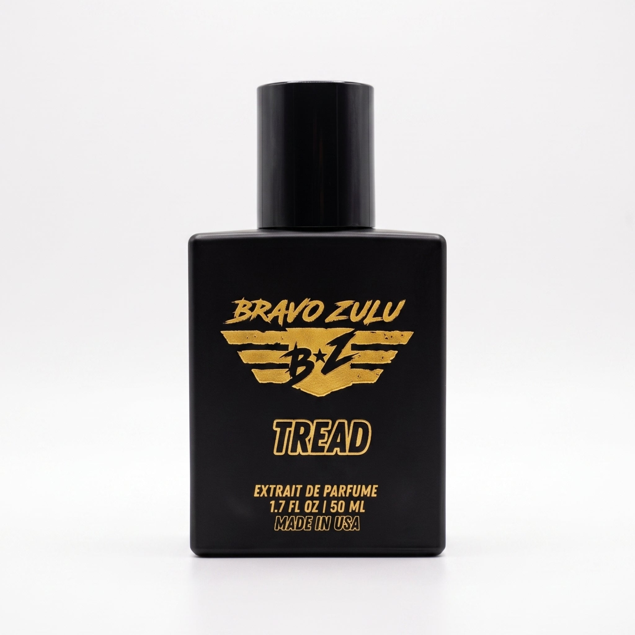 Tactical matte black glass bottle of TREAD Extrait de Parfum by Flagship Soap Company. Features a black atomizer cap and bold yellow Bravo Zulu branding, standing upright against a seamless white background.
