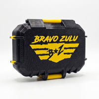 Flagship Soap Company TREAD custom tactical fragrance case shown closed from an angle against a seamless white background. The heavy-duty protective case features a textured matte black finish accented with vibrant strike yellow hardware hinges and a prominent yellow Bravo Zulu winged logo across the front.