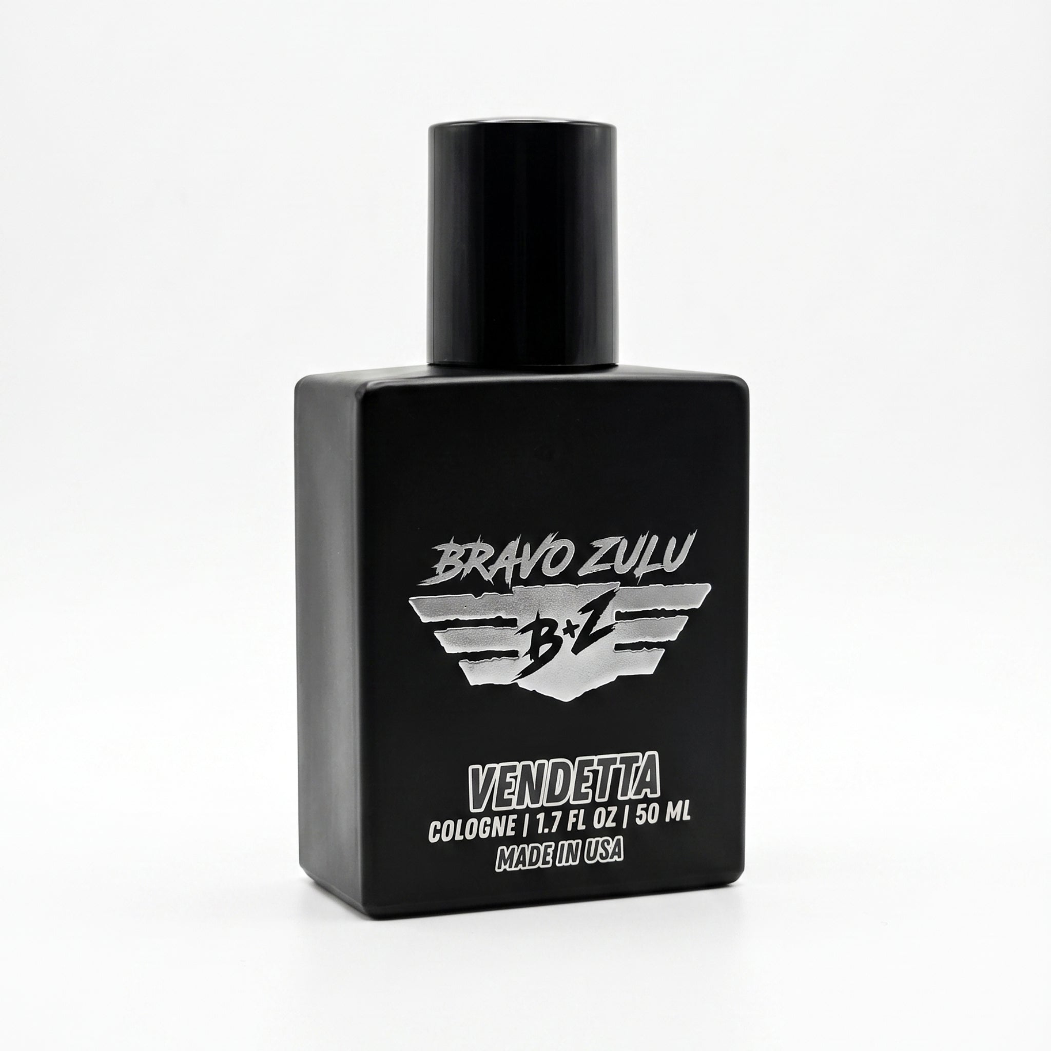 A professional product photograph taken at an angle, showcasing the heavy, tactical matte black glass bottle of Bravo Zulu Vendetta fragrance against a clean white background. The bottle, featuring the distinctive silver winged B+Z logo, stands centered. The label text "BRAVO ZULU" is prominent above the emblem, with "VENDETTA" below it in bold, commanding letters. Smaller white text reads "COLOGNE | 1.7 FL. OZ | 50 ML" and "MADE IN USA". The description identifies this as a massive, true 30% oil concentrat