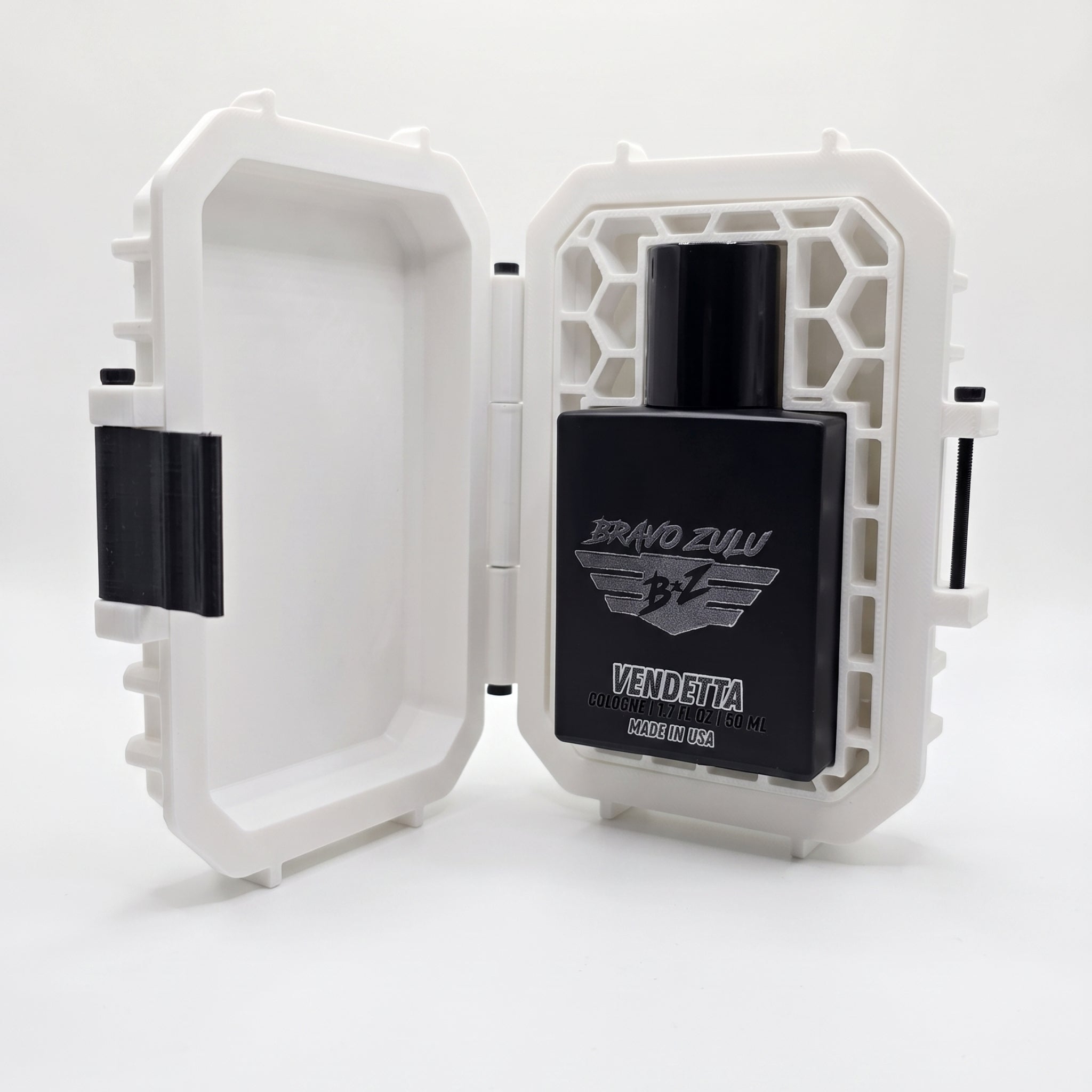 A professional product photograph showcasing the Bravo Zulu VENDETTA fragrance nestled inside its premium presentation hardware against a clean white background.

The heavy, tactical matte black glass bottle is displayed sitting upright inside an open, custom-engineered rugged protective case. The custom tactical case is finished in a clean white color with contrasting black hardware components, featuring a distinctive molded honeycomb pattern on the interior right panel that securely blocks the bottle in p