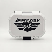 A professional product photograph showcasing the front of the gift-ready custom tactical case for the Bravo Zulu VENDETTA fragrance lineup, displayed on a clean white background.

The custom-engineered rugged protective case features a clean white exterior body with heavy-duty black accent components, including a prominent front-locking latch mechanism at the bottom. The textured white faceplate of the case features a large, starkly contrasting black graphic of the "BRAVO ZULU B★Z" winged shield insignia.


