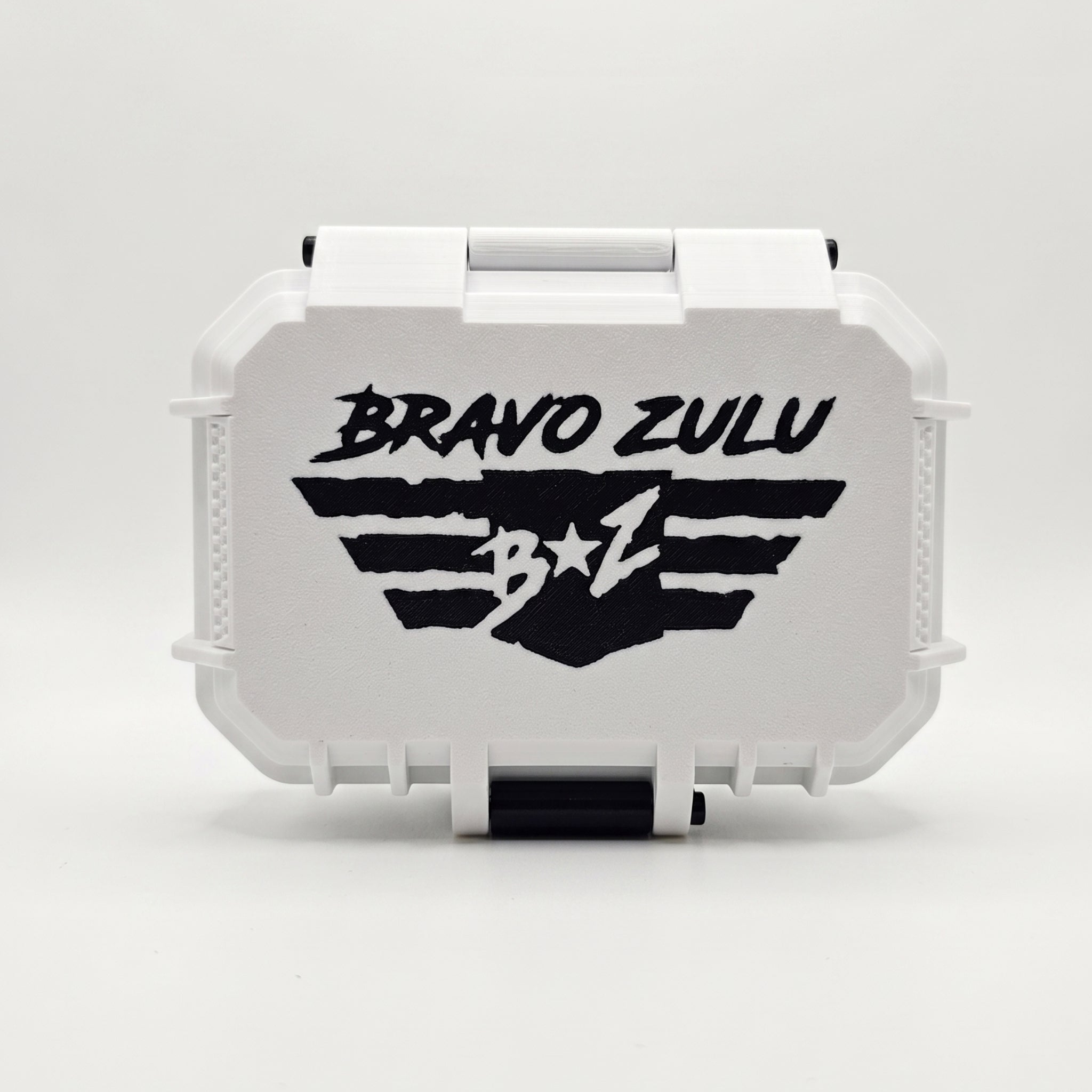 A professional product photograph showcasing the front of the gift-ready custom tactical case for the Bravo Zulu VENDETTA fragrance lineup, displayed on a clean white background.

The custom-engineered rugged protective case features a clean white exterior body with heavy-duty black accent components, including a prominent front-locking latch mechanism at the bottom. The textured white faceplate of the case features a large, starkly contrasting black graphic of the "BRAVO ZULU B★Z" winged shield insignia.

