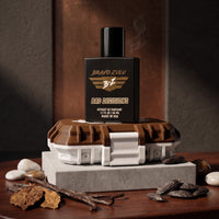 Product image of Bravo Zulu BAD DECISIONS 40ml men's cologne by Flagship Soap Company. The heavy matte black glass bottle is stacked on its custom-engineered rugged protective case. The surrounding natural elements highlight a deep, boozy scent architecture of aged barrel-proof bourbon, charred white oak, rich vanilla bean, and a smooth spice undertone with a commanding 30% oil concentration.