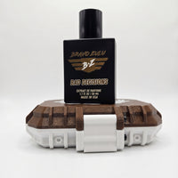 Product catalog image of Bravo Zulu BAD DECISIONS 40ml men's cologne by Flagship Soap Company on a solid white background. The heavy matte black glass bottle is positioned on top of its custom-engineered protective case, representing a 30% fragrance oil concentration with a warm, boozy profile of aged barrel-proof bourbon, charred white oak, and smooth spice.