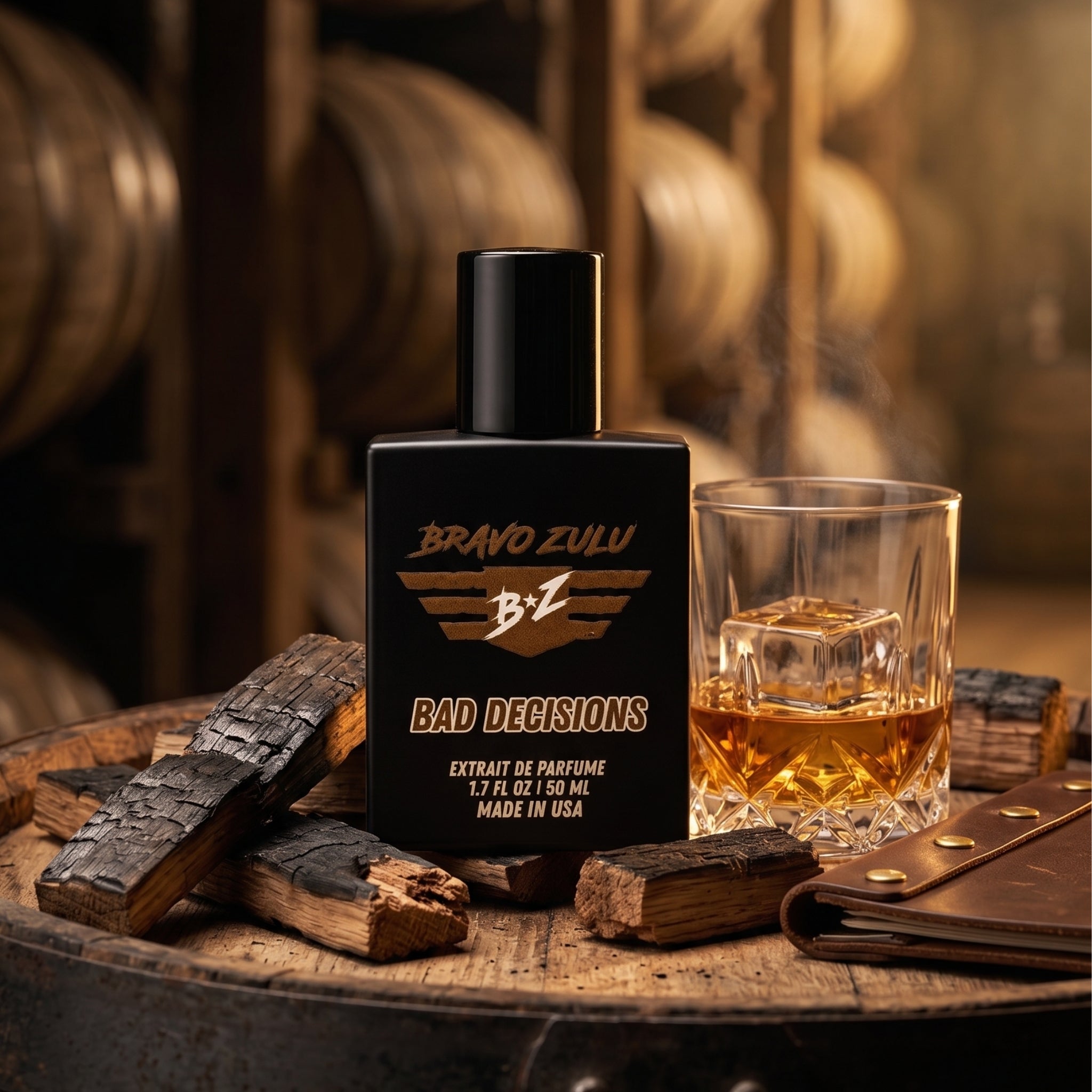 Product shot of Bravo Zulu BAD DECISIONS 40ml men's cologne by Flagship Soap Company. The heavy matte black glass bottle rests on a whiskey barrel in an atmospheric aging cellar, visually evoking a warm, boozy scent architecture of aged barrel-proof bourbon, charred oak wood, rich vanilla bean, and smooth spice delivered at a commanding 30% oil concentration.