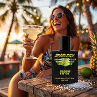 Lifestyle product shot of Bravo Zulu TIPSY Extrait de Parfum by Flagship Soap Company. The matte black glass bottle with lime-green BRAVO ZULU B★Z winged logo and TIPSY branding sits in sharp focus on a rustic wood table scattered with salt, lime, and pineapple, with a laughing woman in sunglasses raising a salted-rim margarita at a palm-lined beach bar at golden-hour sunset in the softly blurred background, evoking the fragrance's boozy tropical gourmand character.