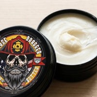 A close-up view of an open 2 oz tin of Hose Dragger beard butter, showing the smooth, whipped white texture of the premium grooming balm next to the firefighter-themed lid.