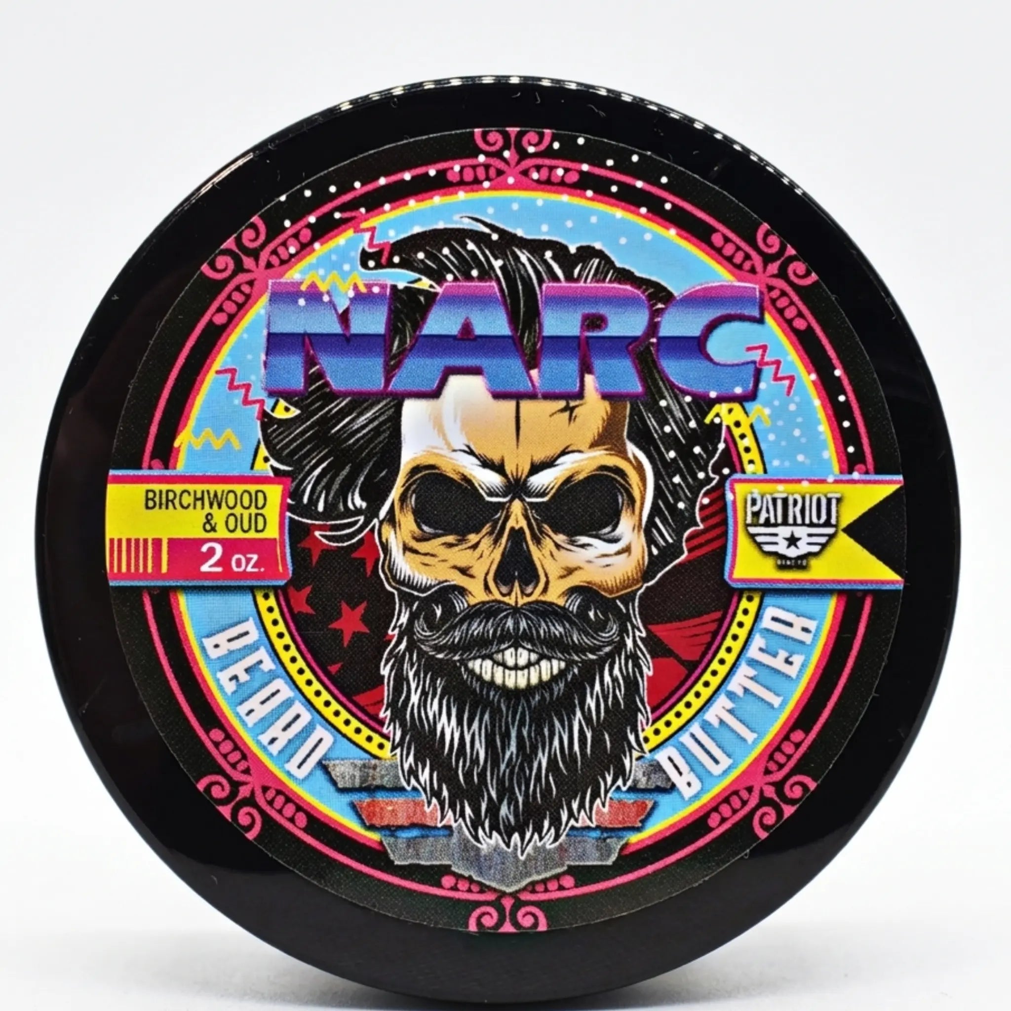 High-resolution product shot of the NARC Birchwood and Oud beard butter lid, featuring a vibrant 80s-inspired bearded skull graphic and Flagship Soap Company’s Patriot branding.