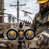 A gritty, atmospheric photograph showing three Flagship Soap 'Dirty Hands Clean Money' beard products arranged on a weathered, grease-stained wooden utility pole crossarm in an outdoor power line work setting. The products are: on the left, a solid black plastic tub of Beard Butter (2oz); in the center, a standing amber glass dropper bottle of Beard Oil (1oz); and on the right, a solid black plastic tub of Beard Balm (2oz). All three products feature a distinct, un-altered label design with a bearded skull 