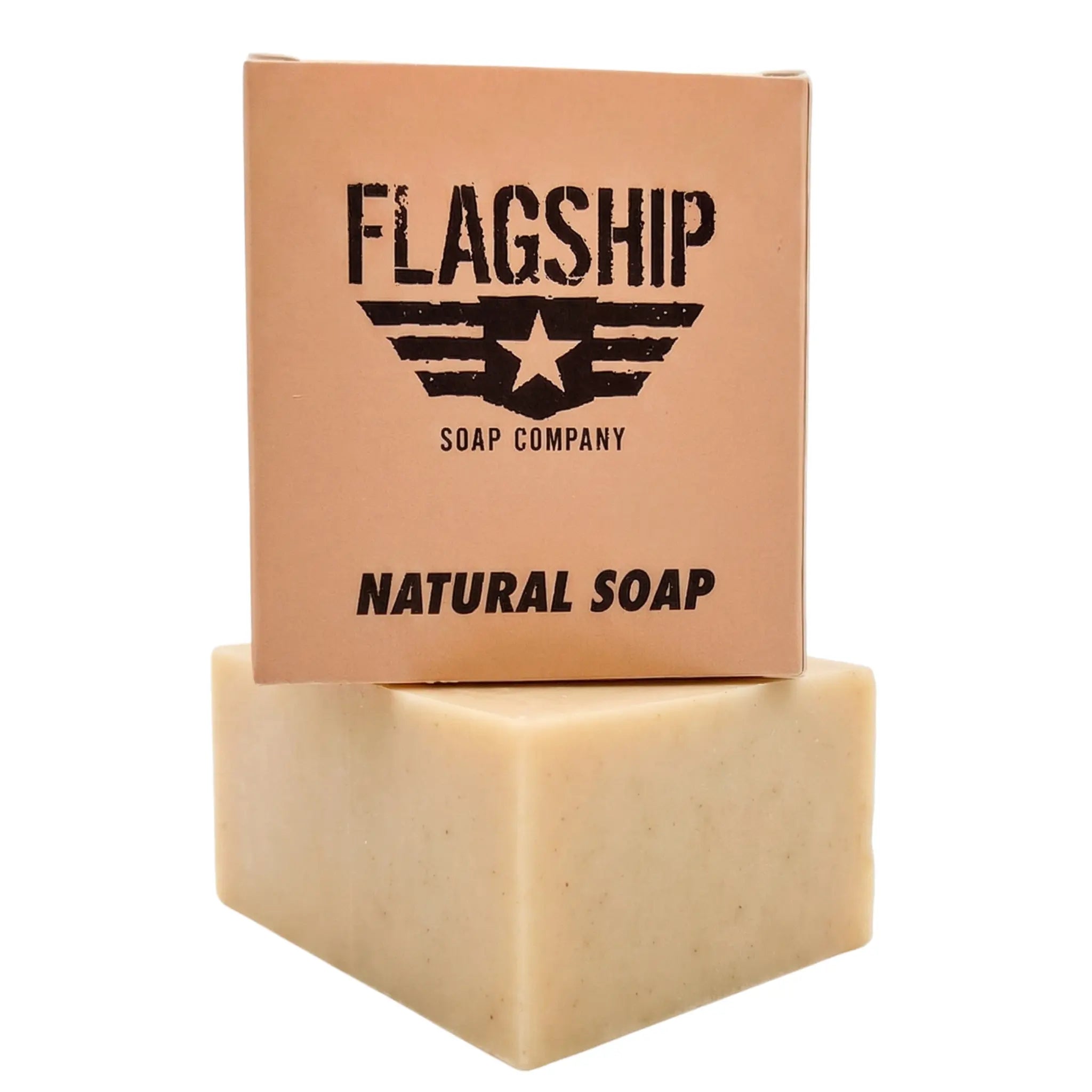 A studio product shot of Holy Grail Natural Soap by Flagship Soap Company. The tan packaging features a bold, stenciled military-style logo with a star and wings, reminiscent of a Meals Ready to Eat (MRE) ration. The box sits atop a thick, artisan-cut bar of cream-colored natural soap against a white background. Designed with a rugged aesthetic, this MRE themed soap makes an excellent gift for any veteran, active-duty service member, or first responder who values high-quality, American-made skin care.