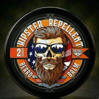 Hipster Repellent Beard Balm 2oz tin. The label features a skull with a pompadour hairstyle, sunglasses reflecting a city skyline, and a manicured beard. A humorous and patriotic grooming product for the traditional man.  Smells like citrus and cedarwood.  A true outdoorsy scent.  